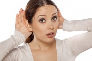 young woman carefully listening with her hands behind the ears