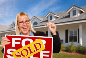 Beautiful Female Holding Keys & Sold Real Estate Sign